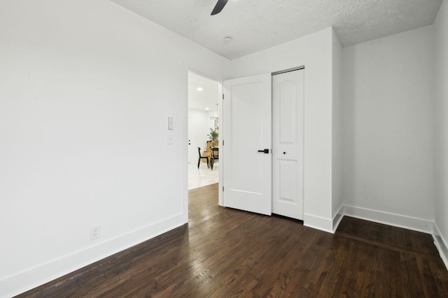 unfurnished bedroom with ceiling fan, dark hardwood / wood-style flooring, a closet, and a textured ceiling