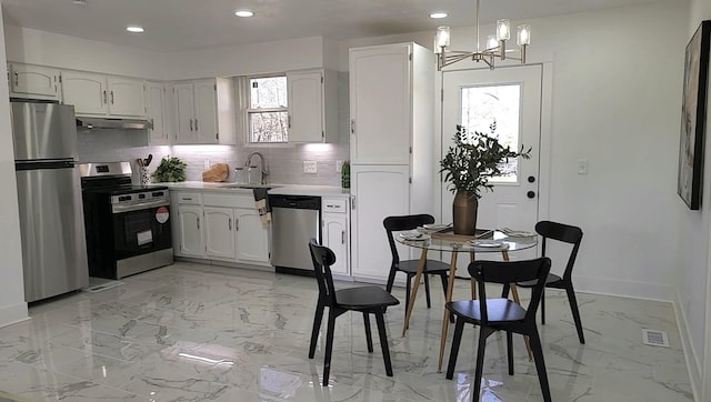 kitchen featuring sink, white cabinetry, tasteful backsplash, decorative light fixtures, and appliances with stainless steel finishes