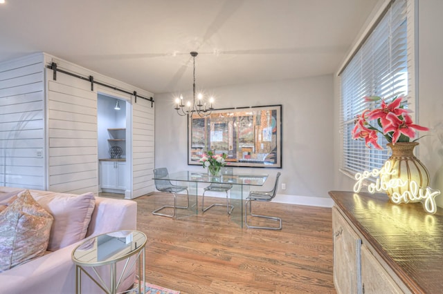 dining space featuring an inviting chandelier, light hardwood / wood-style floors, and a barn door