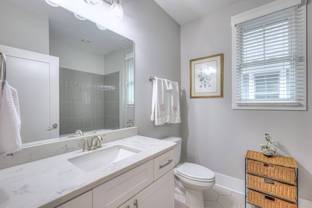 bathroom with tile patterned floors, vanity, toilet, and a tile shower