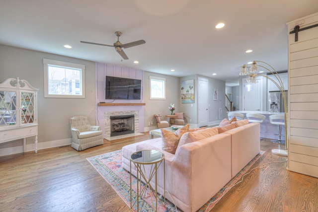 living room featuring light hardwood / wood-style flooring, a barn door, and ceiling fan