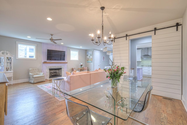 dining space featuring light hardwood / wood-style floors, a barn door, and ceiling fan