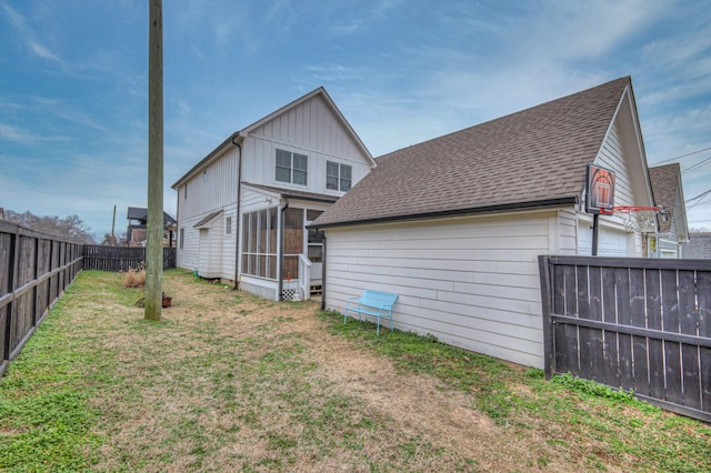 rear view of house featuring a yard and a sunroom