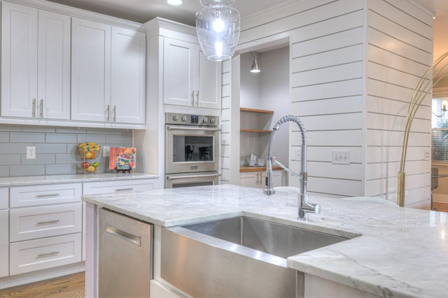 kitchen with light stone countertops, sink, pendant lighting, and white cabinets