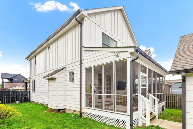 rear view of house with a sunroom and a yard