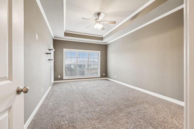 carpeted spare room with crown molding, a tray ceiling, and ceiling fan