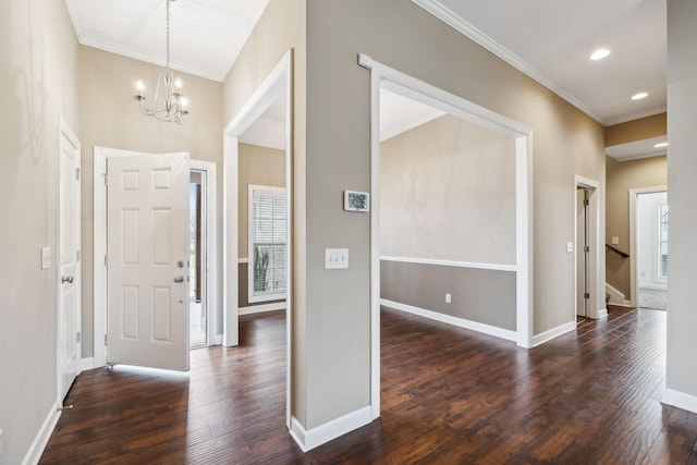 foyer entrance featuring dark hardwood / wood-style flooring, crown molding, and a chandelier