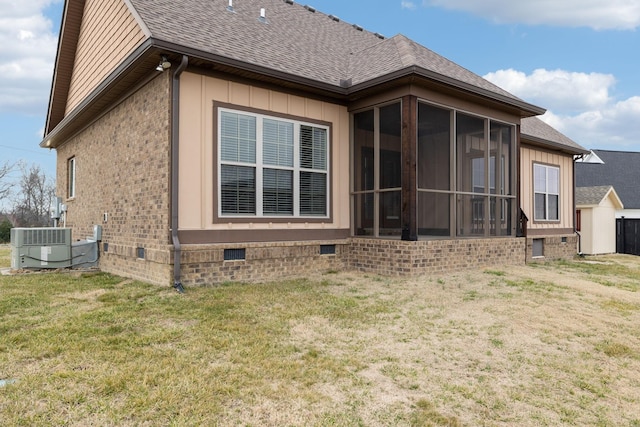 rear view of house with a yard, a sunroom, and central air condition unit