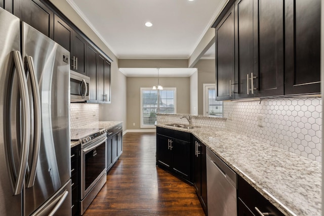 kitchen with appliances with stainless steel finishes, pendant lighting, sink, light stone countertops, and dark wood-type flooring