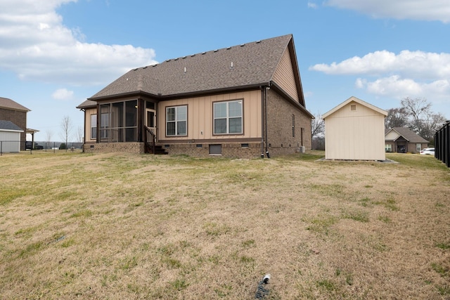 back of house featuring a storage shed, a sunroom, and a lawn