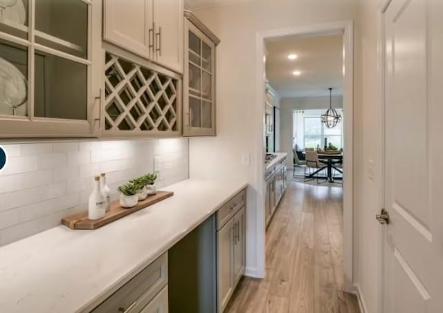 bar featuring pendant lighting, light hardwood / wood-style floors, and backsplash