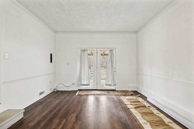 unfurnished room featuring dark hardwood / wood-style floors, a textured ceiling, and french doors