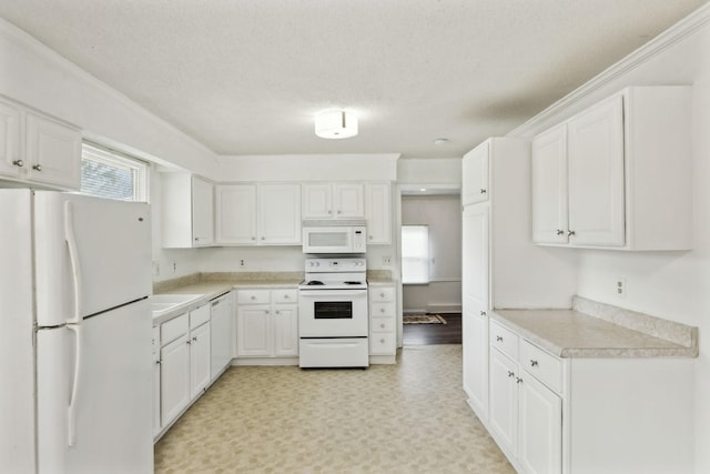 kitchen with white cabinetry, plenty of natural light, a textured ceiling, and white appliances