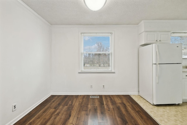 interior space featuring white refrigerator, white cabinetry, plenty of natural light, and dark hardwood / wood-style flooring