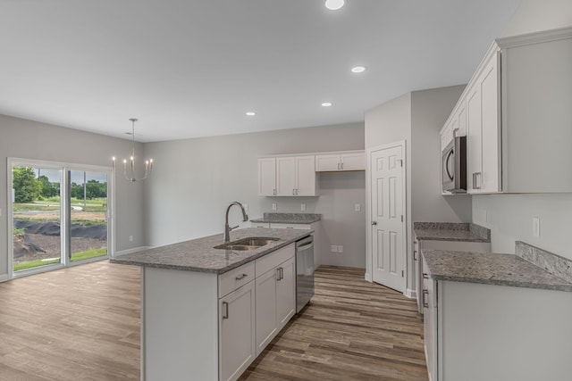 kitchen with sink, white cabinetry, light stone counters, a center island with sink, and stainless steel appliances