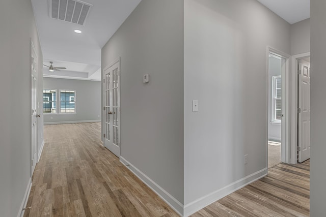 corridor featuring light hardwood / wood-style floors and a raised ceiling