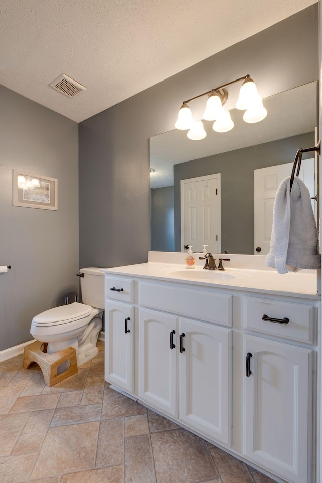 bathroom with vanity, a textured ceiling, and toilet