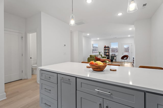 kitchen with gray cabinetry, decorative light fixtures, and light hardwood / wood-style flooring