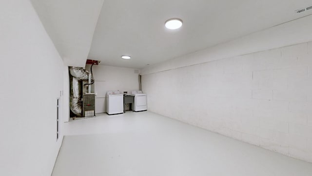 basement featuring heating unit and washer and clothes dryer