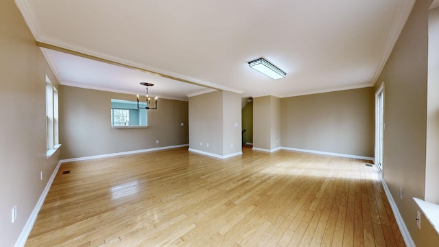 empty room featuring an inviting chandelier, ornamental molding, and light hardwood / wood-style flooring