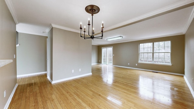 empty room featuring crown molding, light hardwood / wood-style floors, and a chandelier