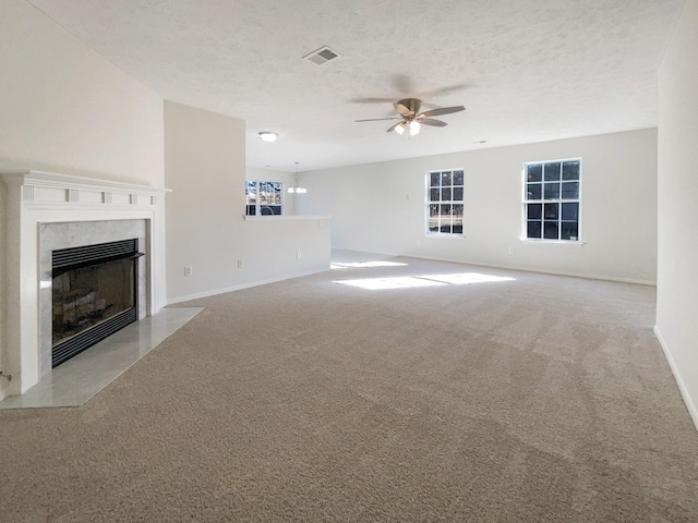 unfurnished living room featuring ceiling fan, light colored carpet, a premium fireplace, and a textured ceiling