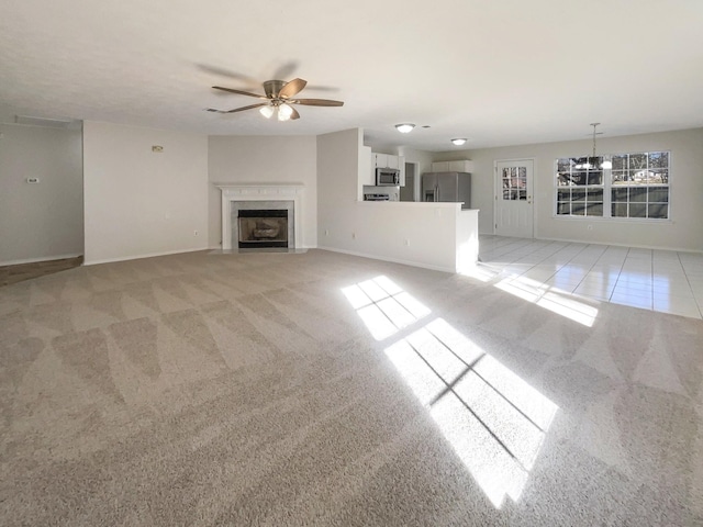 unfurnished living room featuring light colored carpet and ceiling fan with notable chandelier