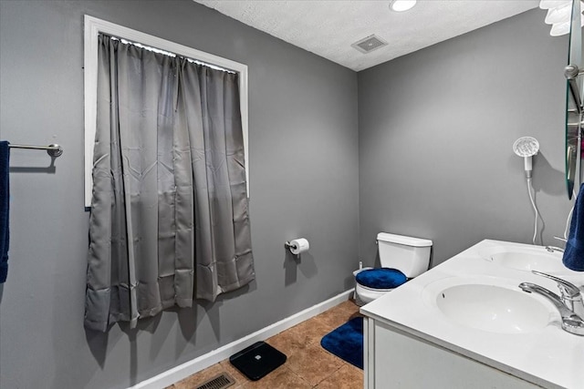 bathroom with tile patterned flooring, vanity, a textured ceiling, and toilet