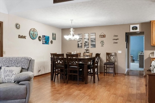 dining area featuring a chandelier, a textured ceiling, and light hardwood / wood-style floors