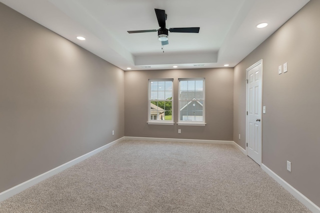 unfurnished room with light colored carpet, ceiling fan, and a tray ceiling