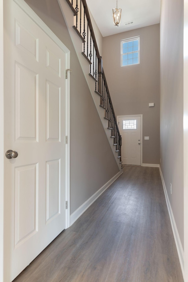 foyer entrance with a high ceiling, a healthy amount of sunlight, hardwood / wood-style floors, and an inviting chandelier