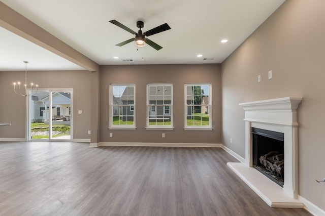 unfurnished living room with ceiling fan with notable chandelier and dark hardwood / wood-style flooring