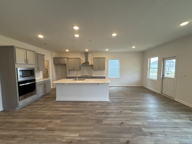 kitchen with wall chimney range hood, gray cabinets, stainless steel appliances, and sink