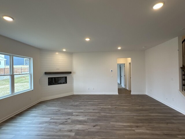 unfurnished living room with a large fireplace and dark hardwood / wood-style flooring