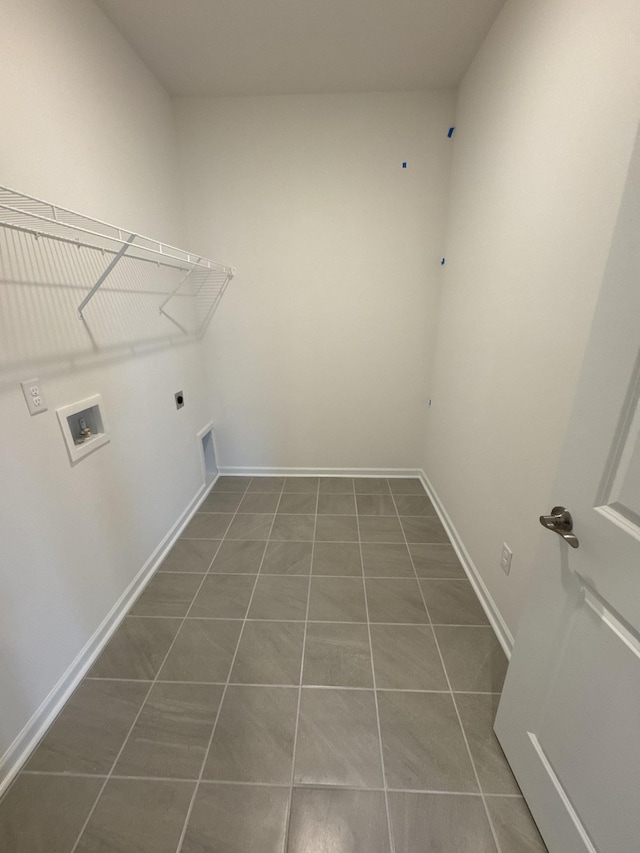 clothes washing area with hookup for an electric dryer, dark tile patterned flooring, and hookup for a washing machine