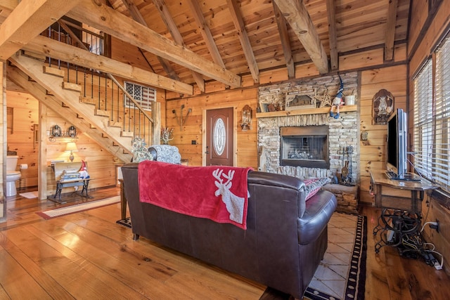 living room with beam ceiling, hardwood / wood-style floors, wood ceiling, and wooden walls