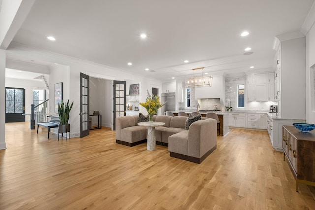 living room featuring crown molding, light hardwood / wood-style floors, and french doors