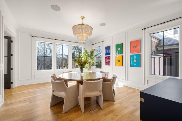 dining area with light hardwood / wood-style floors and a chandelier