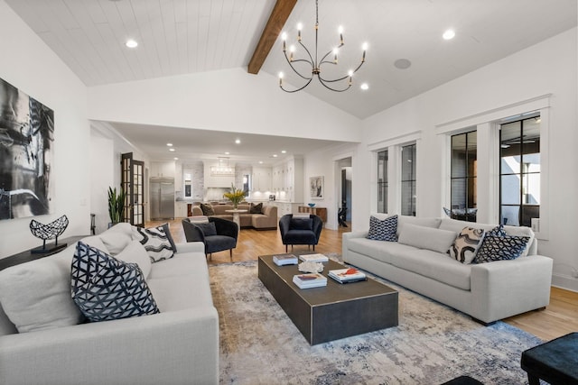 living room featuring beam ceiling, high vaulted ceiling, an inviting chandelier, and light wood-type flooring