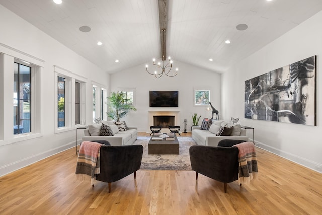 living room featuring an inviting chandelier, a wealth of natural light, light hardwood / wood-style floors, and beamed ceiling