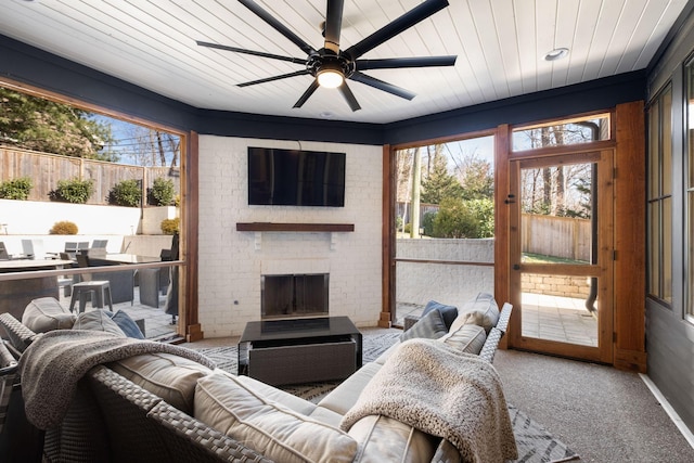 living room with brick wall, carpet, a fireplace, and ceiling fan