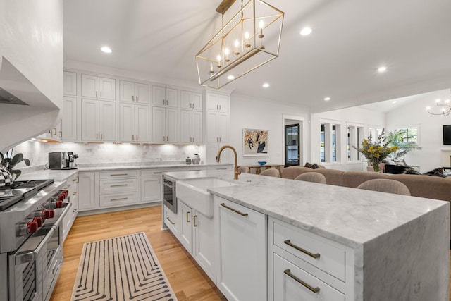 kitchen with white cabinets, decorative light fixtures, light hardwood / wood-style floors, and a spacious island