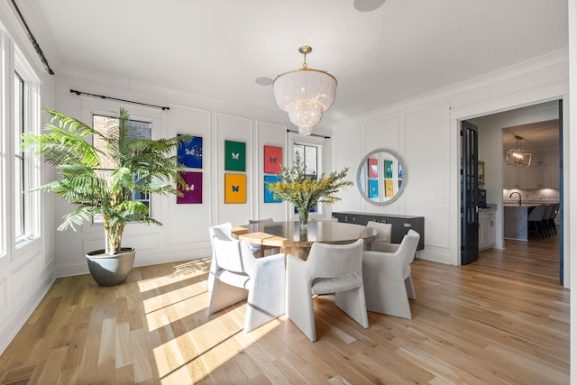 dining room featuring ornamental molding, an inviting chandelier, and light hardwood / wood-style floors