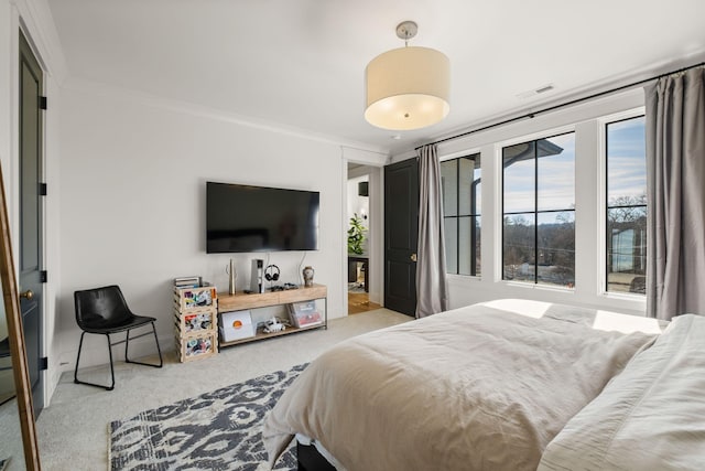 bedroom with ornamental molding and light carpet