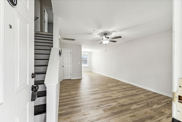 interior space featuring ceiling fan with notable chandelier and light hardwood / wood-style floors