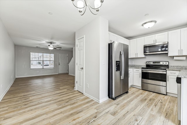 kitchen with light wood-type flooring, appliances with stainless steel finishes, ceiling fan, light stone countertops, and white cabinets