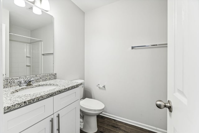 bathroom featuring hardwood / wood-style flooring, vanity, walk in shower, and toilet