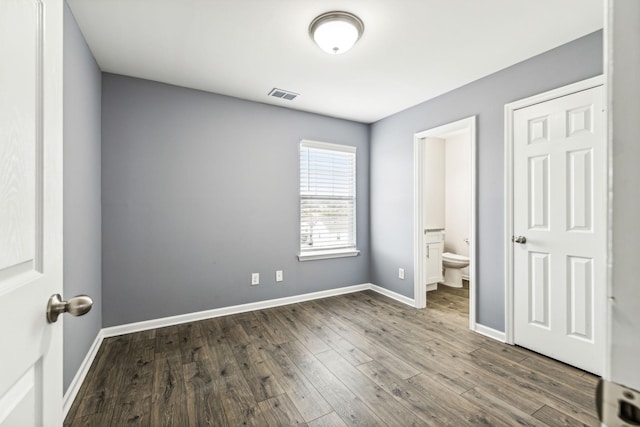 unfurnished bedroom featuring dark hardwood / wood-style flooring and ensuite bath