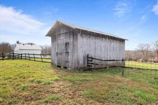 view of outbuilding featuring a rural view and a lawn