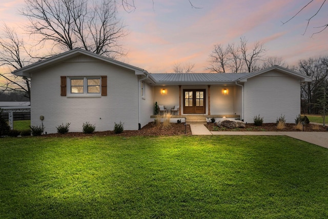 ranch-style house with french doors, a porch, and a lawn